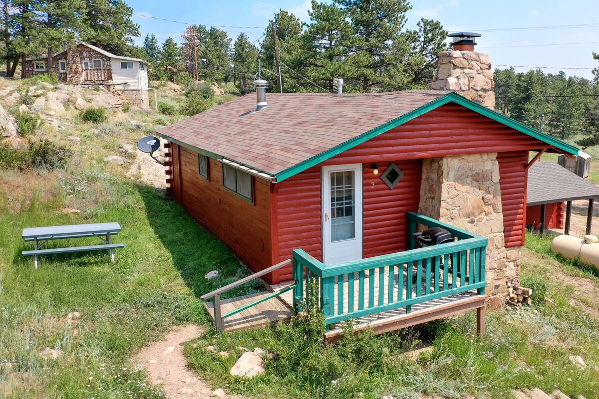A small, red log cabin with a stone chimney, a porch, and a number '2' sign.