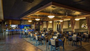 Un restaurante espacioso con múltiples mesas y sillas, una zona de bar y un gran acuario al fondo.