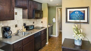 Una cocina con armarios de madera oscura, un microondas, una cafetera y un lavabo. En la pared hay un cartel enmarcado que dice "LONDON BRIDGE".