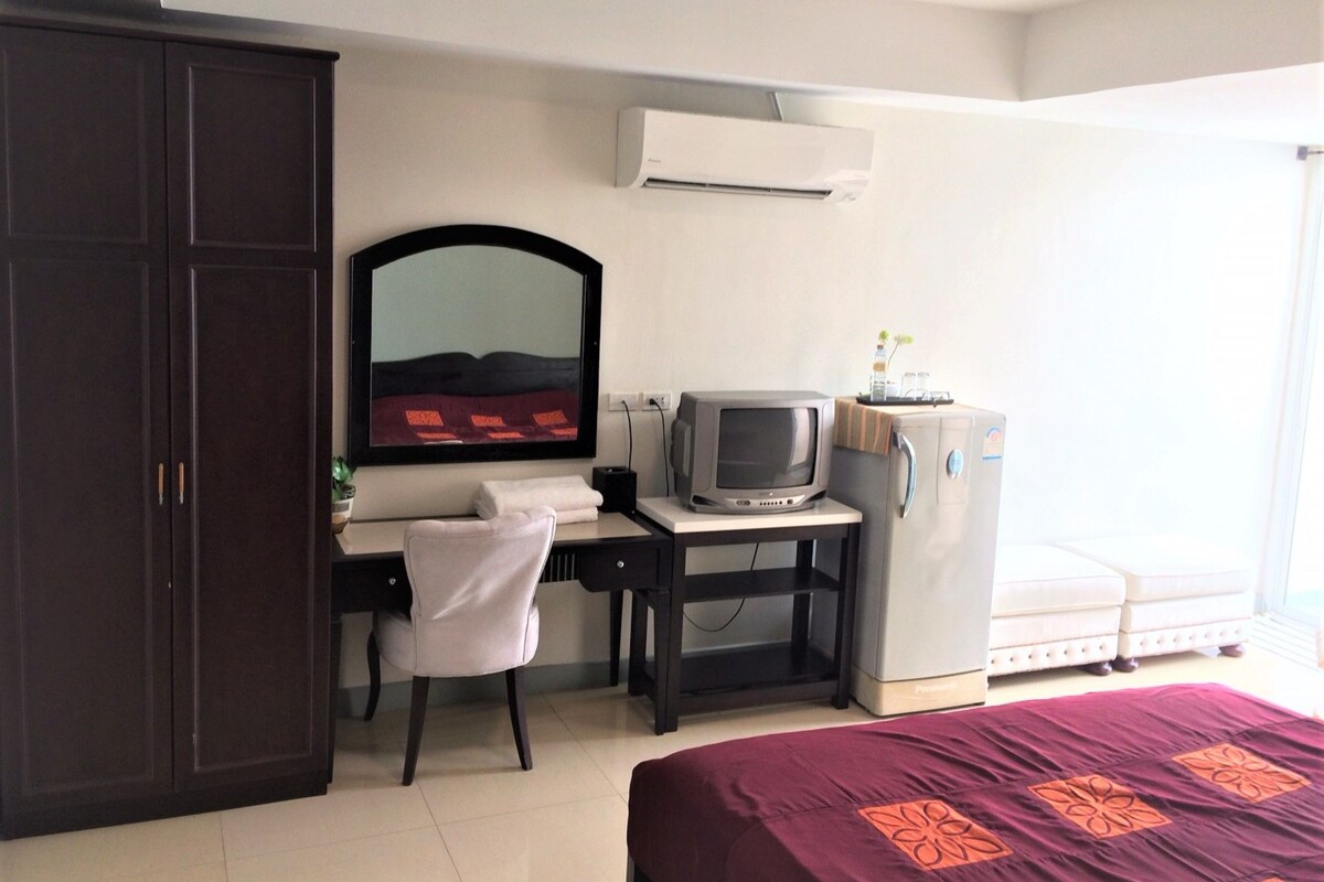 Habitación de hotel con cama, escritorio con silla, televisión, armario y ventana.