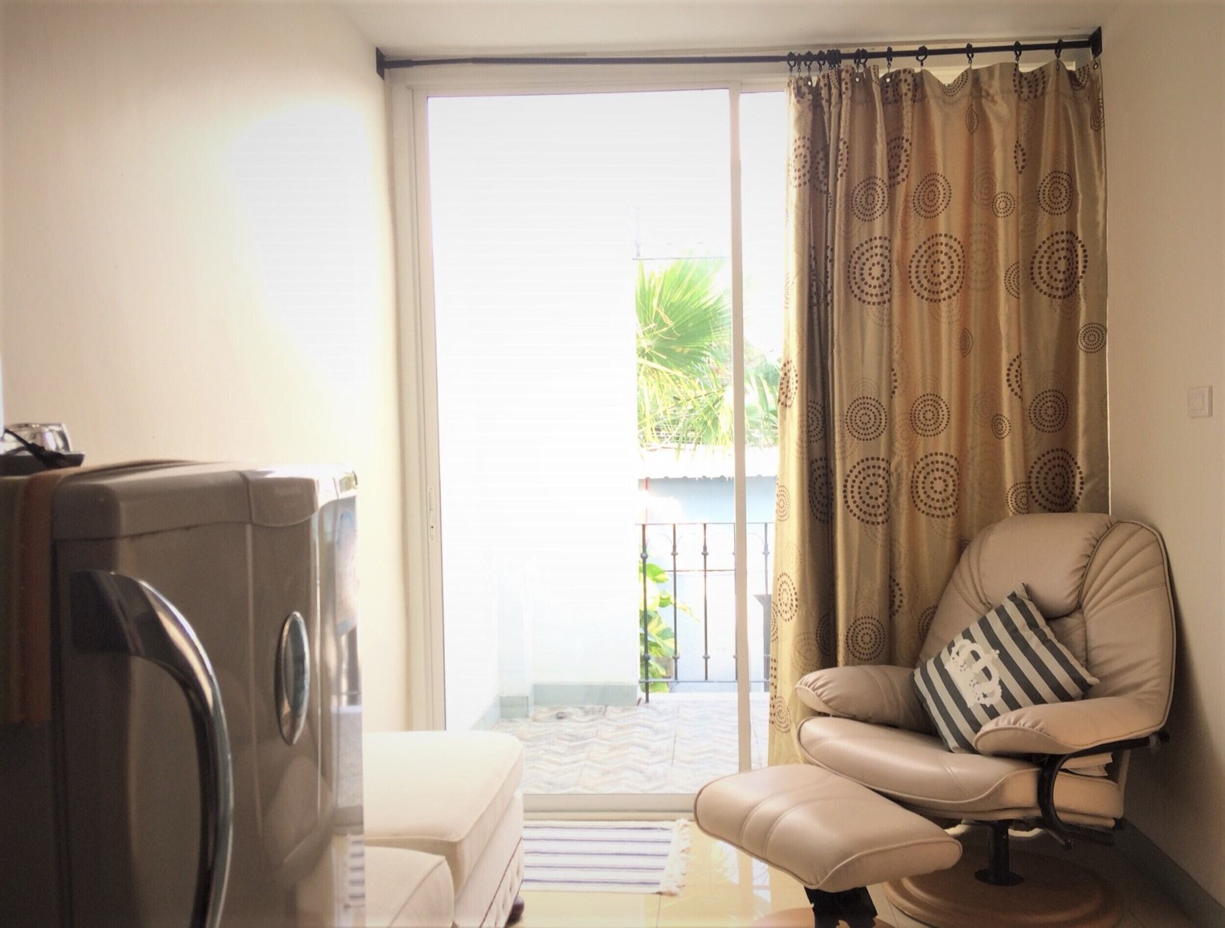 A living room with a sofa, a television, and a sliding glass door leading to a balcony.