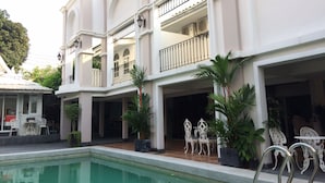 A multi-story building with a swimming pool, outdoor seating, and potted plants. - Wong Amat House by Zuzu (Pattaya)