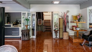 A spacious living area with a polished wooden floor, a staircase leading to an upper level, and a variety of decorative items including plants and artwork. - Wong Amat House by Zuzu (Pattaya)