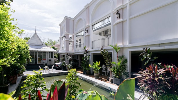 A courtyard with a pool, potted plants, and a white building with balconies. - Wong Amat House by Zuzu (Pattaya)