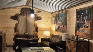 A rustic wooden interior with a dining area, a large wooden sculpture, and two framed wildlife paintings.