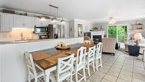 A modern kitchen with white cabinetry, stainless steel appliances, and a central island with seating.