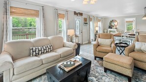 A spacious living room with a large window overlooking a lake, a ceiling fan, and a cozy seating area with a coffee table.