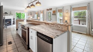 A modern kitchen with a granite countertop, stainless steel appliances, and pendant lighting.