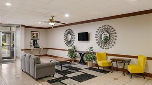 A lobby with a sofa, chairs, a coffee station, and decorative wall mirrors. - Alice Western Inn (Alice)