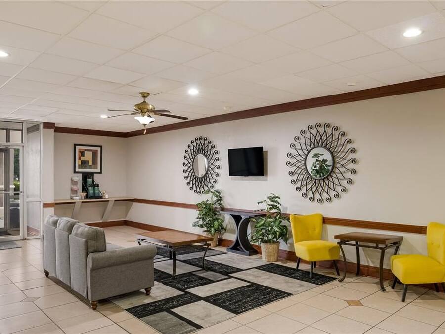 A lobby with a sofa, chairs, a coffee station, and decorative wall mirrors.