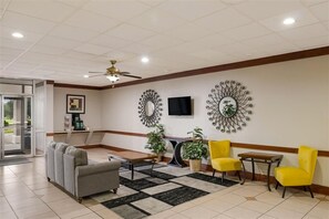 A lobby with a sofa, chairs, a coffee station, and decorative wall mirrors. - Alice Western Inn (Alice)