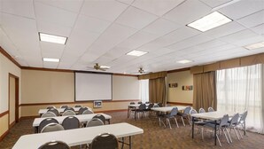A conference room with multiple tables and chairs, a projector screen, and a ceiling fan. - Quality Inn Alice (Alice)