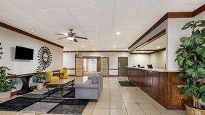 A hotel lobby with a reception desk, seating area, and a ceiling fan. - Quality Inn Alice (Alice)