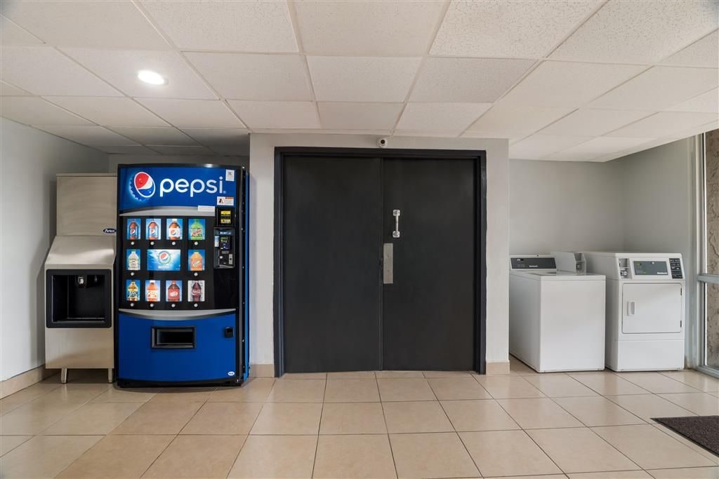 En automat med Pepsi-logo, en sort dør og to vaskemaskiner.
