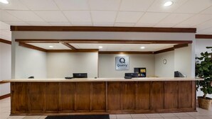 A reception desk with a sign that reads 'Quality' and a clock on the wall. - Quality Inn Alice (Alice)