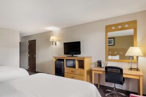 A hotel room with a bed, a desk with a computer, a television, and a mirror. - Alice Western Inn (Alice)