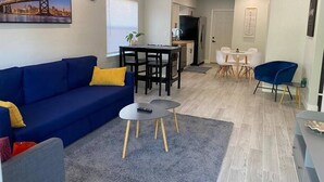 A modern living room with a blue sofa, a small round table, and a ceiling fan.