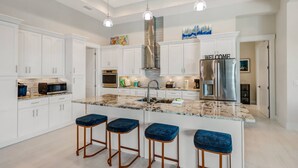 A modern kitchen with white cabinetry, a stainless steel refrigerator, and a granite countertop. - 401 Old Burnt Store Rd N (Cape Coral)