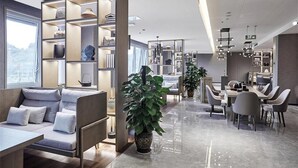 A modern interior with a sofa, dining area, and shelves with decorative items. - Howard Johnson by Wyndham Tianxiaqiguan Hotel Xingwen (Yibin)