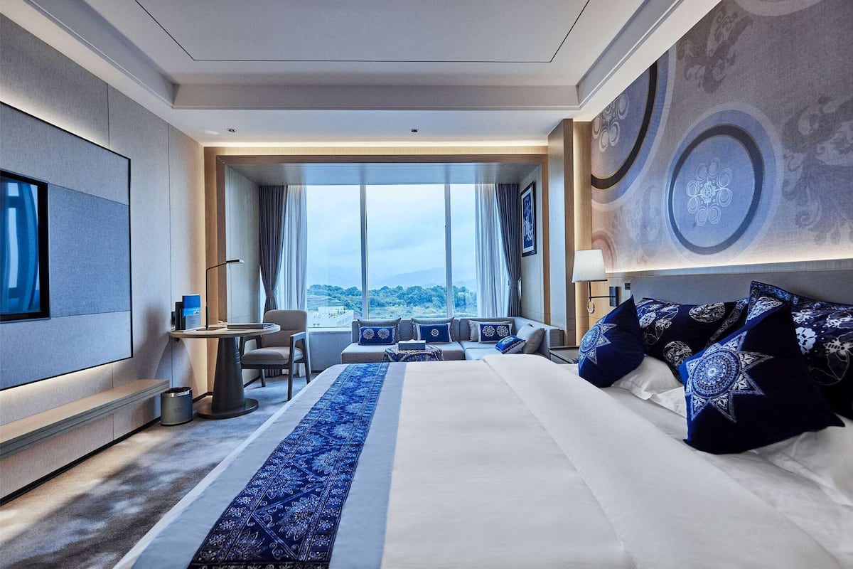 Ett modernt hotellrum med en stor säng, ett skrivbord och utsikt över staden.