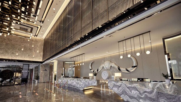 A spacious lobby with a marble reception desk, modern lighting fixtures, and a large decorative wall piece. - Howard Johnson by Wyndham Tianxiaqiguan Hotel Xingwen (Yibin)