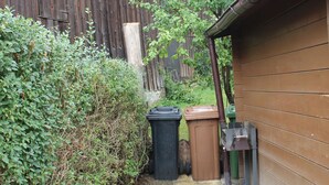 A narrow paved pathway leading to a wooden building with a brown exterior. - W.I.L.A. 1 (Helmbrechts)