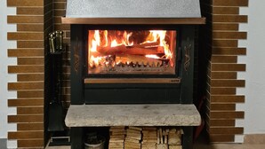 A modern fireplace with a stone facade and a metal vent above the fire. - W.I.L.A. 1 (Helmbrechts)