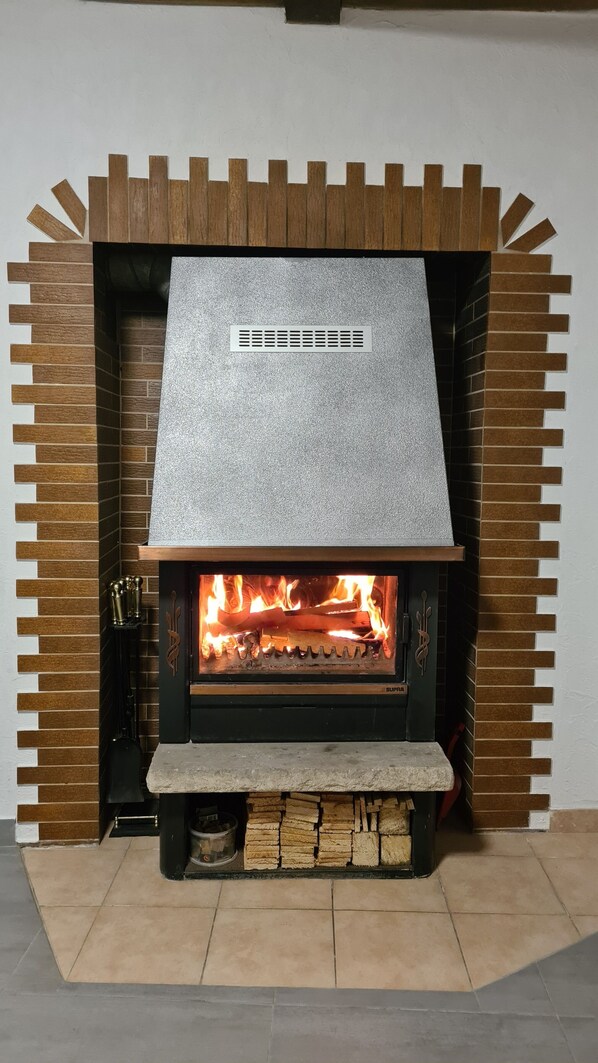 A modern fireplace with a stone facade and a metal vent above the fire. - W.I.L.A. 1 (Helmbrechts)