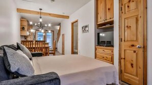 Une chambre à coucher comprenant un lit, une armoire en bois et un coin repas avec une table et des chaises.