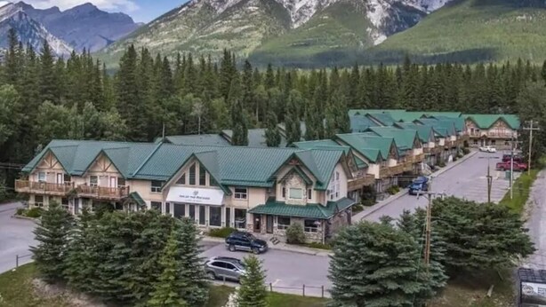 Un chalet avec une rangée de cabanes, un bâtiment principal portant une enseigne, et un paysage montagneux en arrière-plan.