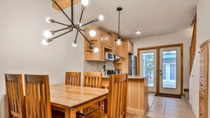 Une cuisine moderne avec des meubles en bois, une table à manger avec des chaises et un luminaire au plafond original.