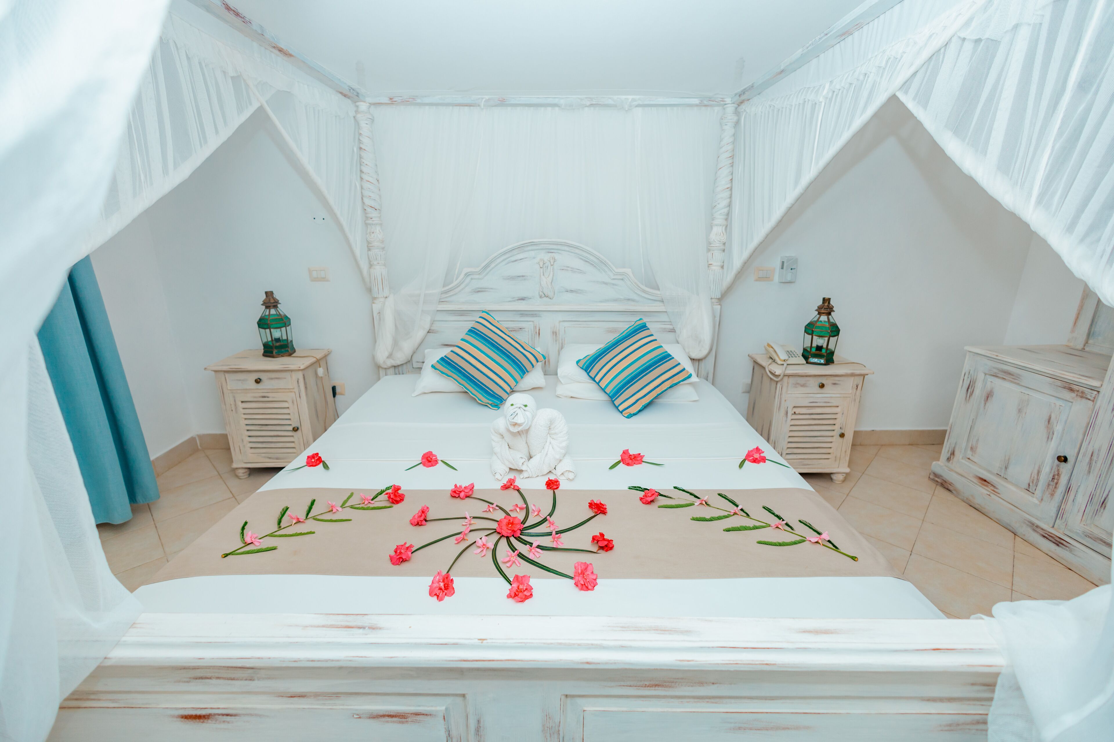 A bedroom with a canopy bed, two nightstands, and a decorative statue.