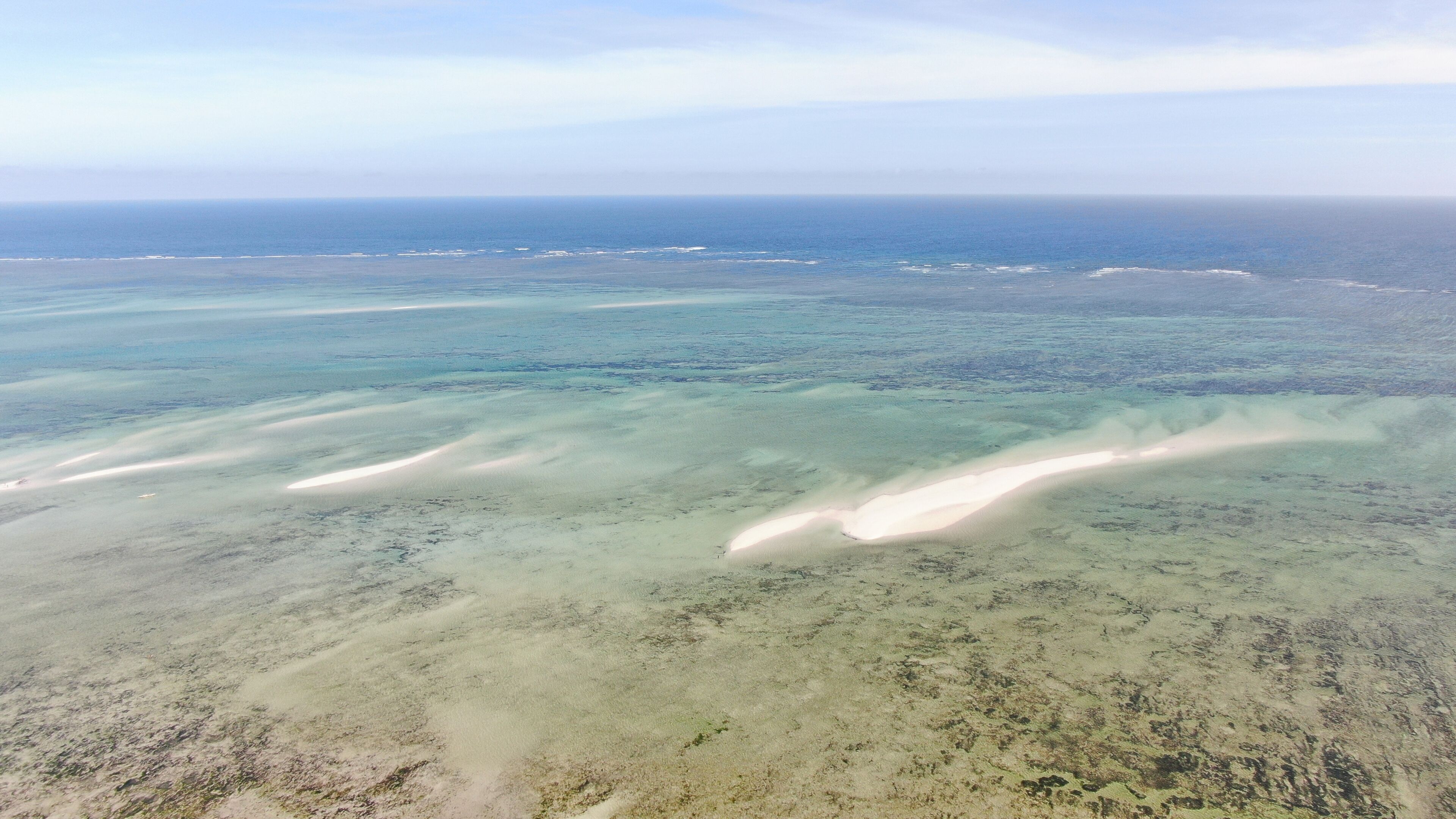 An aerial view of a coastal area with clear waters and sandy beaches.