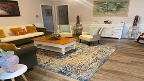 Ein Wohnzimmer mit einer Couch, Sesseln, einem Couchtisch und einem gemusterten Teppich.