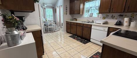 A kitchen with wooden cabinets, a dishwasher, and a dining area with a table and chairs.
