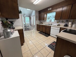 A kitchen with wooden cabinets, a dishwasher, and a dining area with a table and chairs. - Spacious Peaceful Home 3BR 2BA,Quiet Neighborhood (Valdosta)