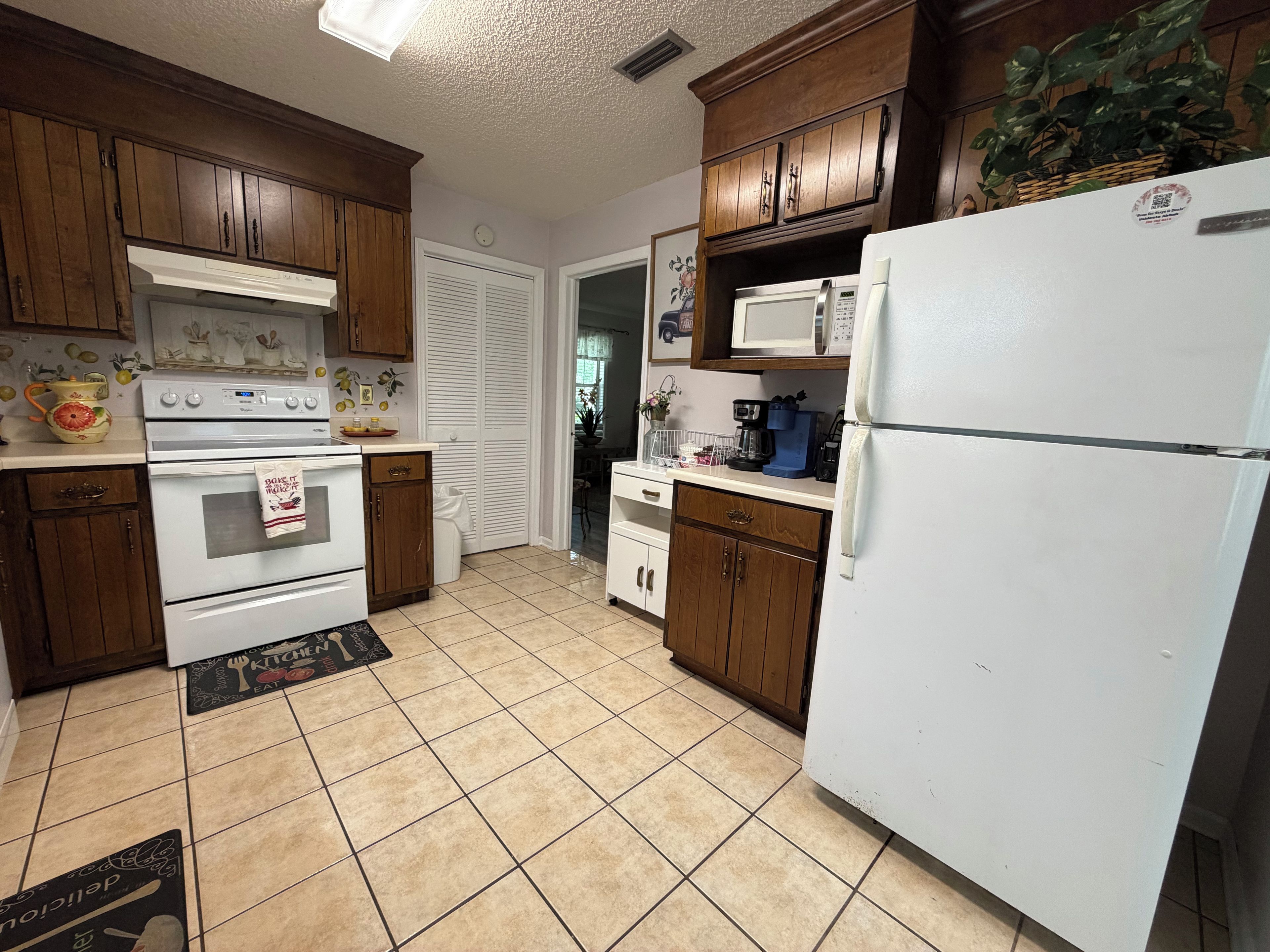 A kitchen with wooden cabinets, a white refrigerator, a stove, and a microwave.