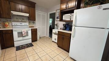 A kitchen with wooden cabinets, a white refrigerator, a stove, and a microwave.