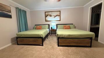 A bedroom with two beds, a ceiling fan, a painting, and a nightstand with a lamp.