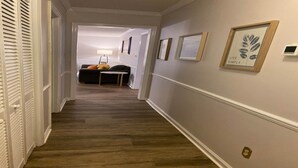 Ein Flur mit Holzboden, einer Couch, einem Tisch und gerahmten Bildern an den Wänden.