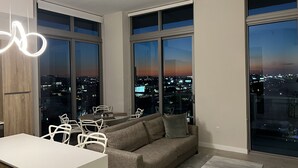 Una sala de estar moderna con un ventanal grande, un sofá, una mesa de comedor y sillas.