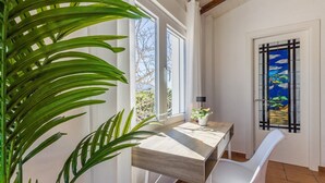 A room with a wooden desk, white chair, and a large window with a view of trees. - El Reposo Alhaurín de la Torre by Ruralidays (Málaga)