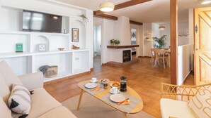 A modern living room with a sofa, coffee table, and dining area. There is a fireplace, a TV mounted on the wall, and a plant on the shelf. - El Reposo Alhaurín de la Torre by Ruralidays (Málaga)