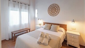 A neatly arranged bedroom with a large bed, bedside tables, a bench, and a decorative wall piece. - El Reposo Alhaurín de la Torre by Ruralidays (Málaga)
