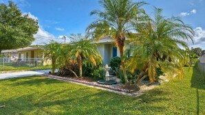 A residential property with a well-maintained lawn, palm trees, and a fountain.
