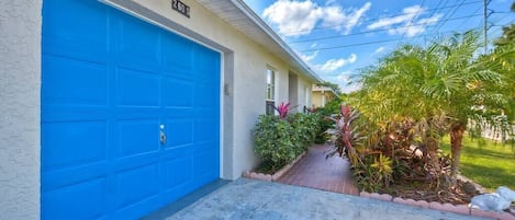 A building with a blue garage door, a number '260' sign, and a small garden with various plants.