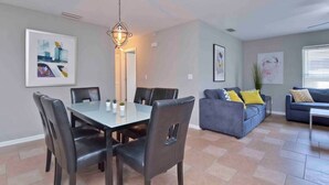 A modern living room with a dining area, grey walls, and a large window.