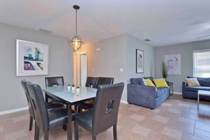 A dining area with a table and chairs, a sofa, and a coffee table in a living room.