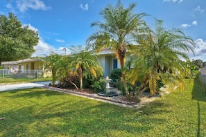 A residential property with a well-maintained lawn, palm trees, and a fountain.