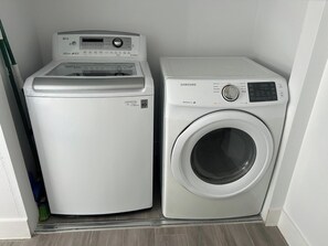 A compact laundry room with a front-loading washer and a top-loading dryer.